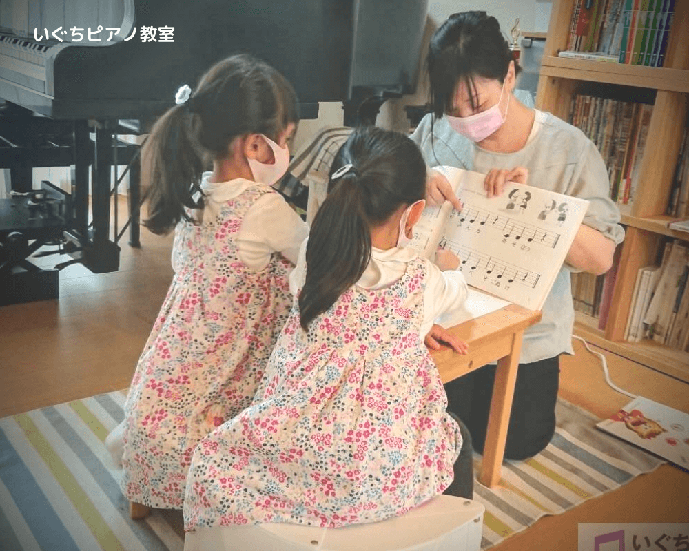 幼児の生徒さんに楽譜を見せながら話をしている画像