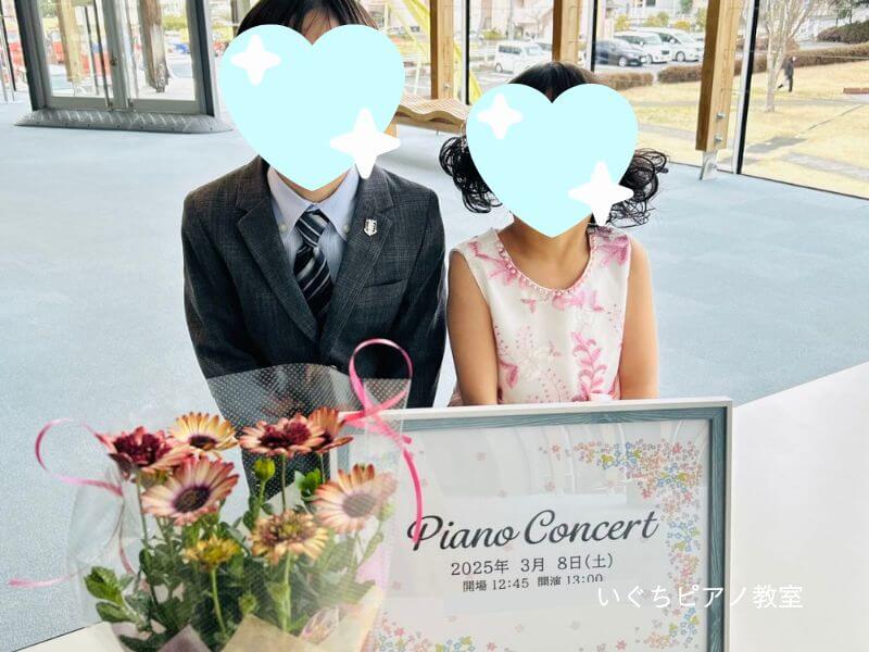 いぐちピアノ教室の看板の前でポーズを決めている生徒さんの画像
